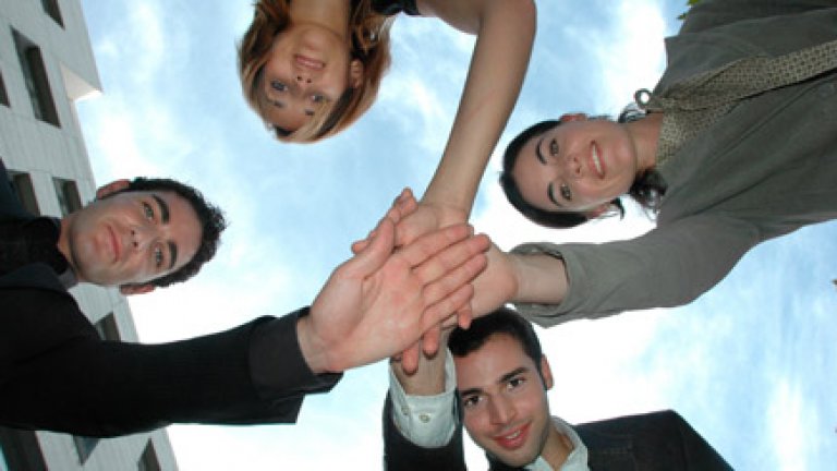 young_business_people_looking_down_stacking_hands